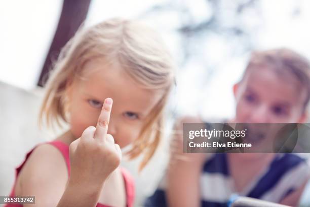 girl-holding-up-a-middle-finger-with-shocked-sibling-in-the-background.jpg